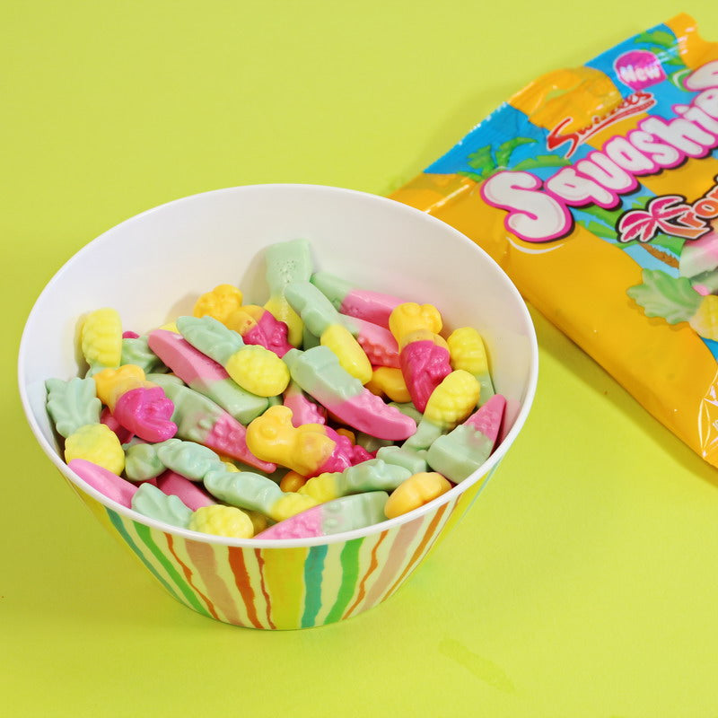 Colorful gummy candies in a bowl with a Squashies packaging on a green background