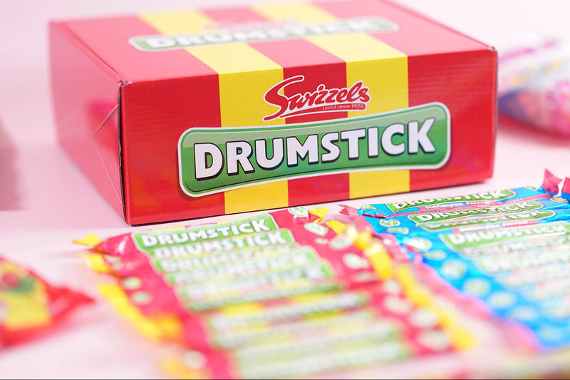 Box of Swizzels Drumstick candy with colorful packaging on a pink background