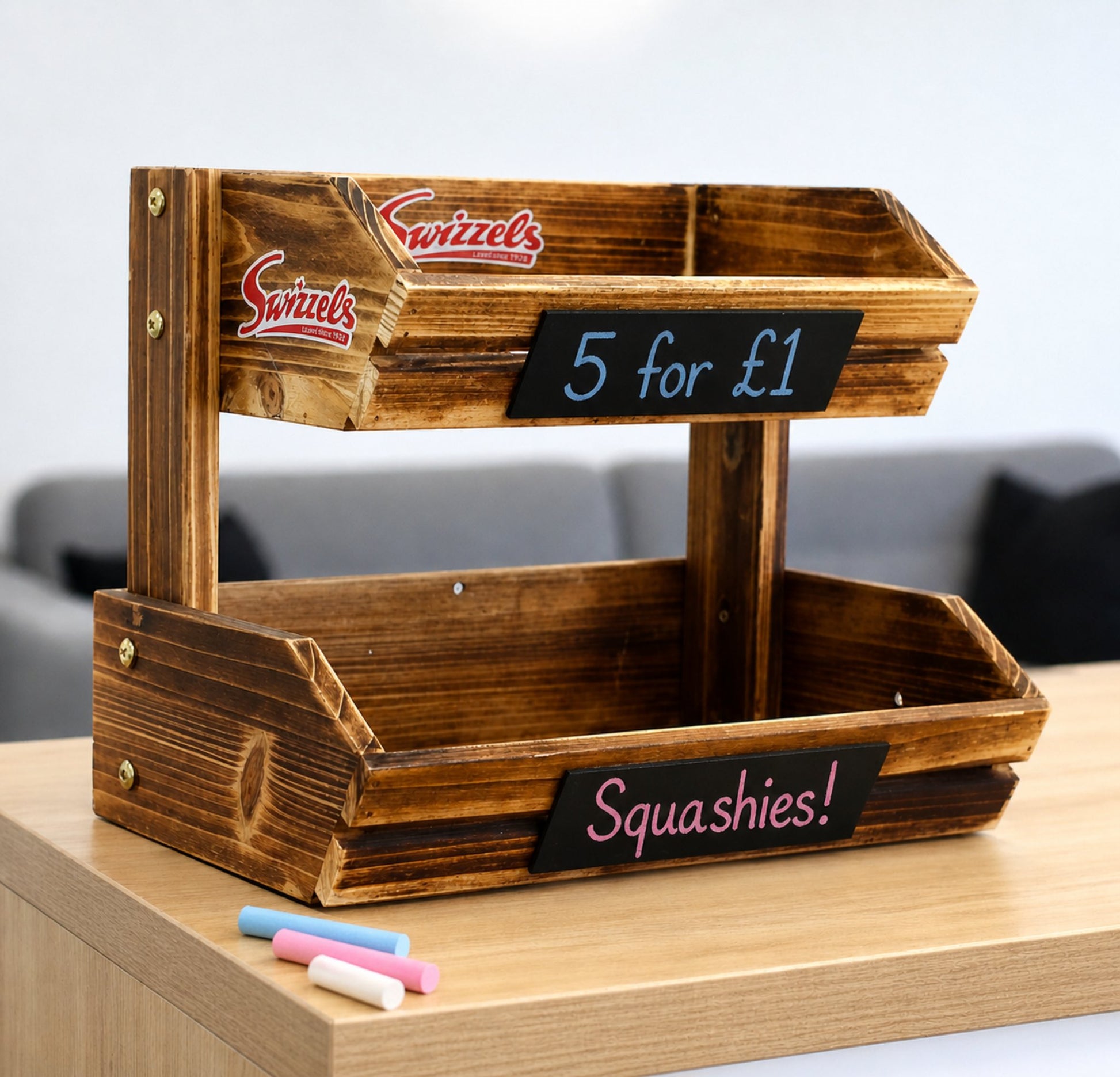 Wooden display stand with 'Swizzles' branding and chalkboard labels on a wooden surface.