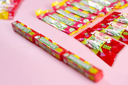Several red and yellow Dr. Dreisick Menthol 1000 gum sticks and single packets arranged on a light pink background.