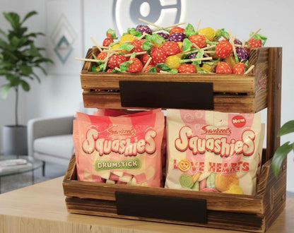 Wooden crate with Sweeties Squashies candy drumsticks and love hearts on a table.