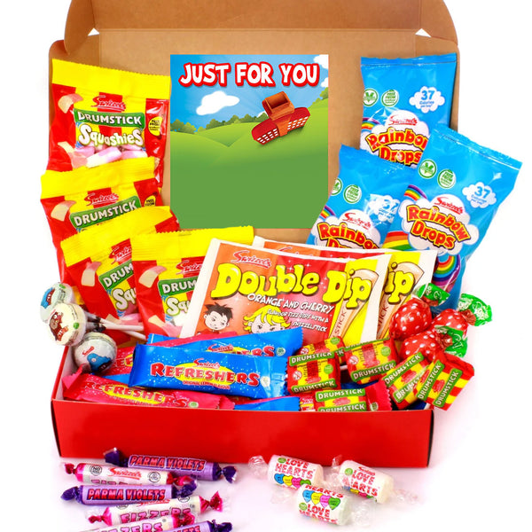 A candy and snack gift box filled with assorted packaged sweets and lollipops, including Rainba Drops, Drumstick, Double Dip, and Refreshments, arranged in an open brown cardboard box with a 'Just For You' card, on a white background.