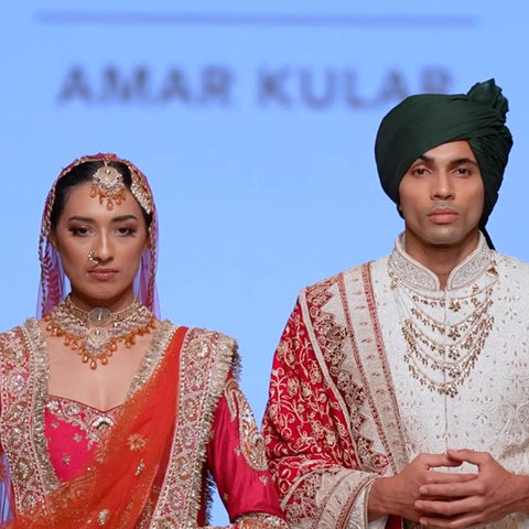 Two models in traditional Indian attire on a runway with 'Amar Kular' branding.