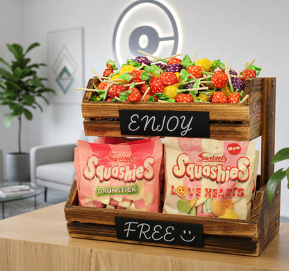 Wooden crate with assorted candies and 'Squashies' packages on a table.