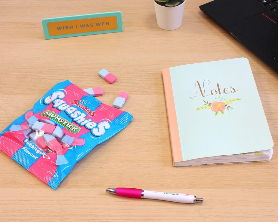 Desk with Squishies packaging, notebook, pen, and laptop.