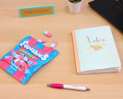Desk with Squishies packaging, notebook, pen, and laptop.