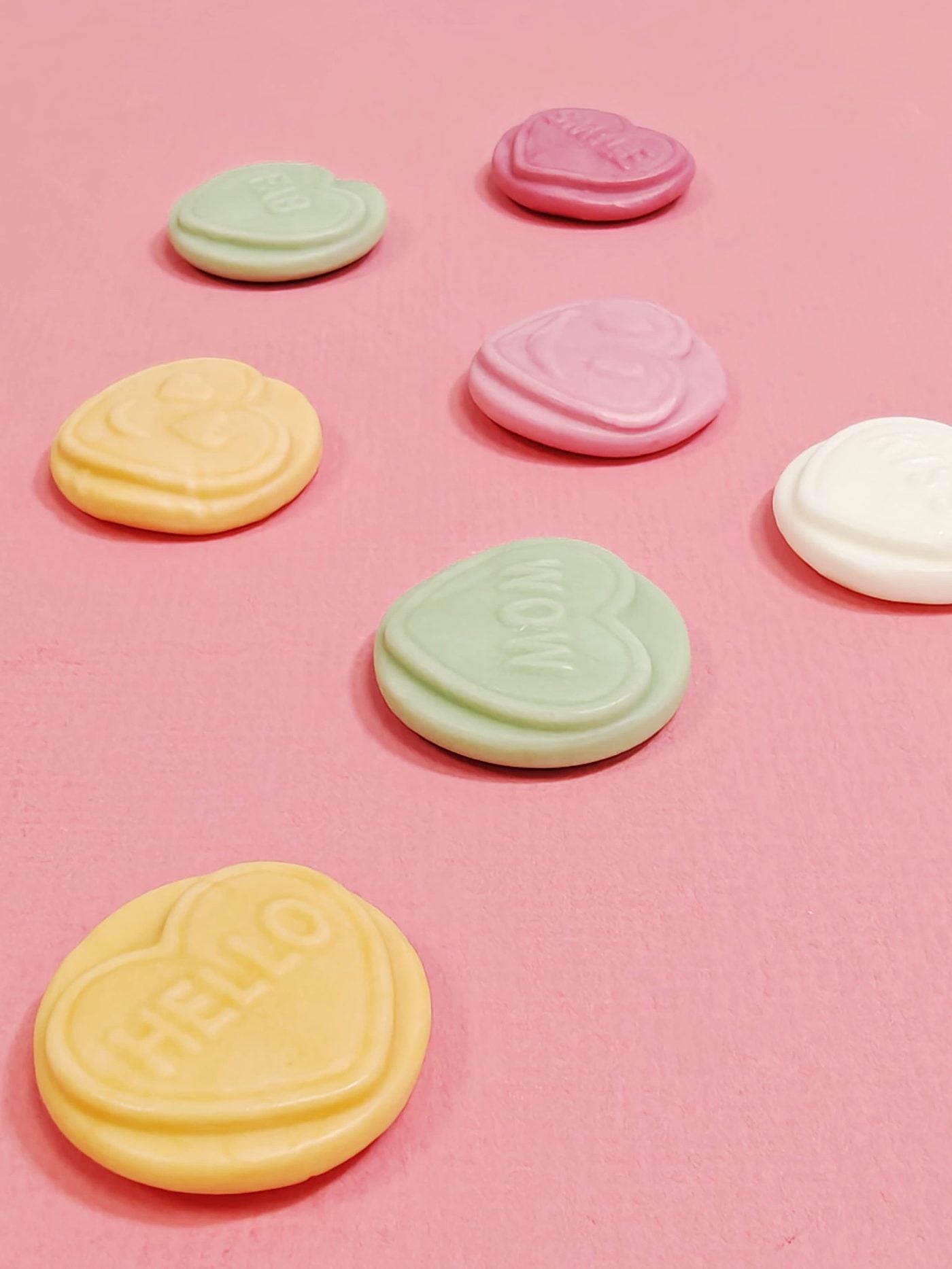 Heart-shaped candy pieces on a pink background