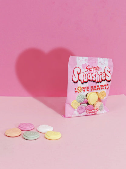 Sweets Squashies Love Hearts packaging with heart-shaped shadows on a pink background
